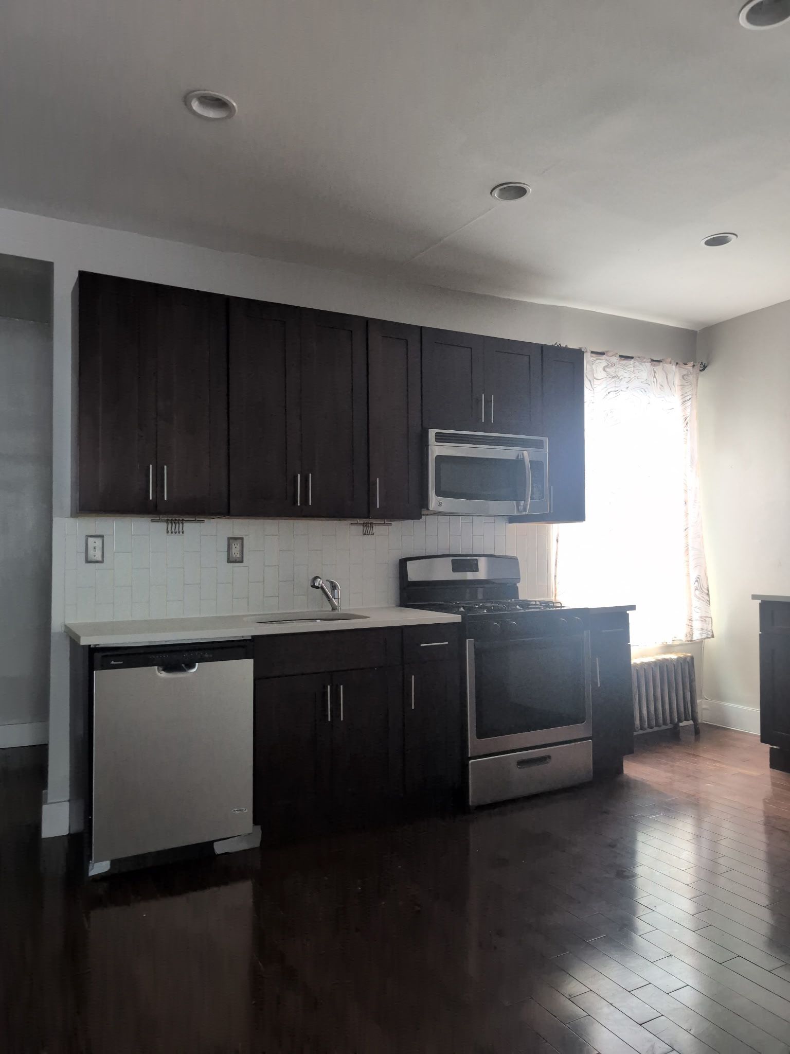 2405 Nostrand Avenue, Unit 6 Brooklyn, NY 11210 - Photo 1 of 11 a kitchen with granite countertop wooden cabinets and black stainless steel appliances