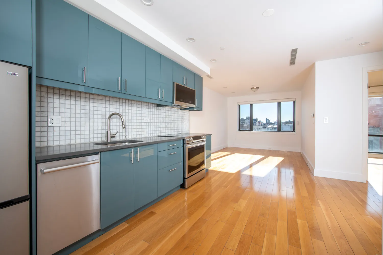 a kitchen with a sink a microwave cabinets and wooden floor