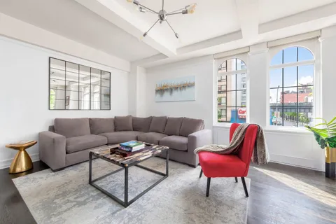 a living room with furniture a large window and a wooden floor