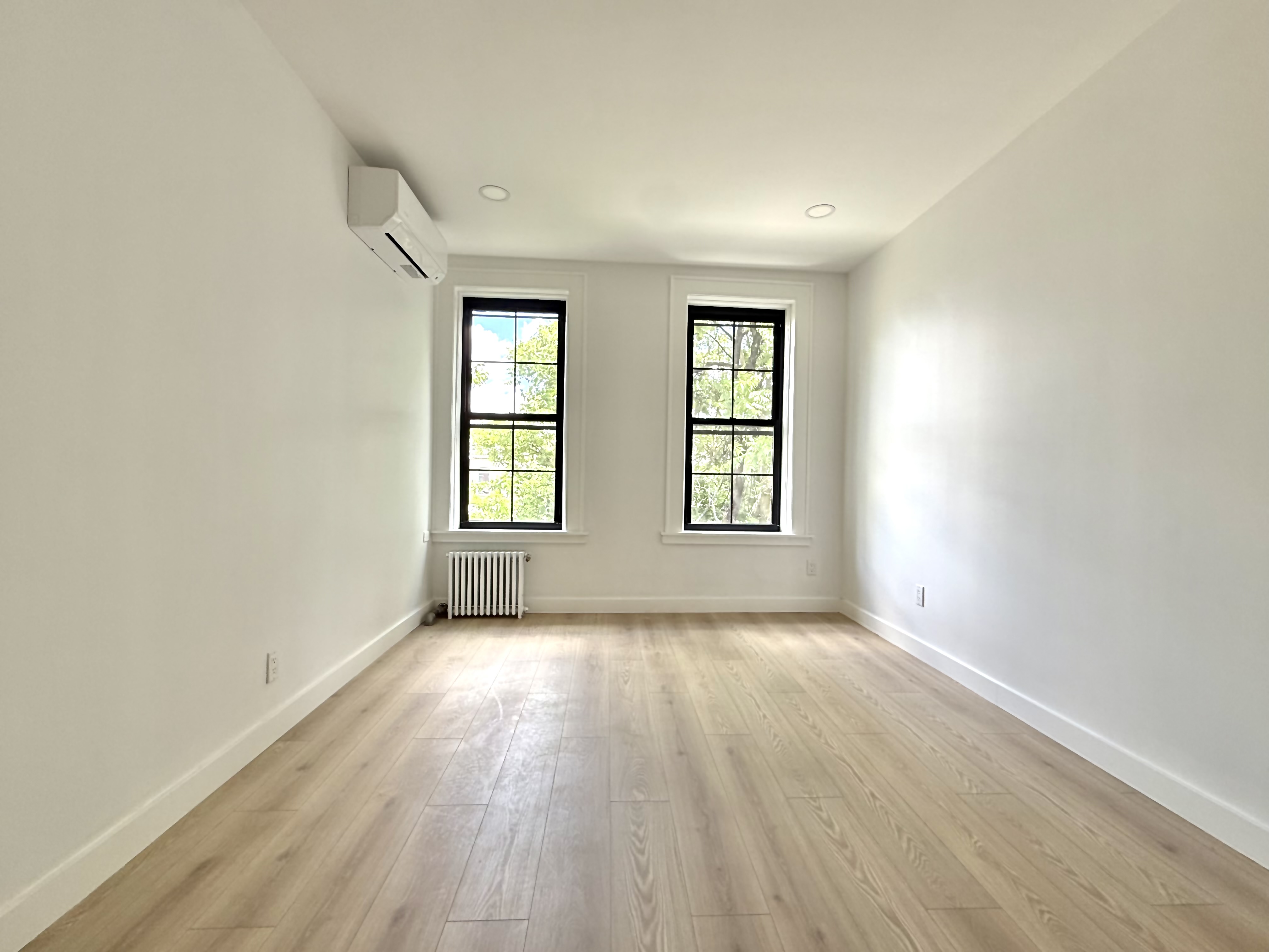 985 Rogers Avenue, Unit 3 Brooklyn, NY 11226 - Photo 4 of 10 an empty room with wooden floor and windows