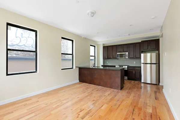 a view of an empty room with wooden floor and a bathroom view