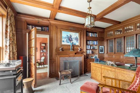 a view of a hallway to a livingroom with furniture wooden floor windows and a chandelier