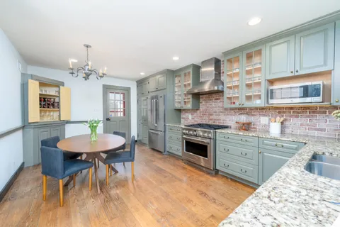a kitchen with stainless steel appliances granite countertop a kitchen island hardwood floor sink stove dining table and chairs