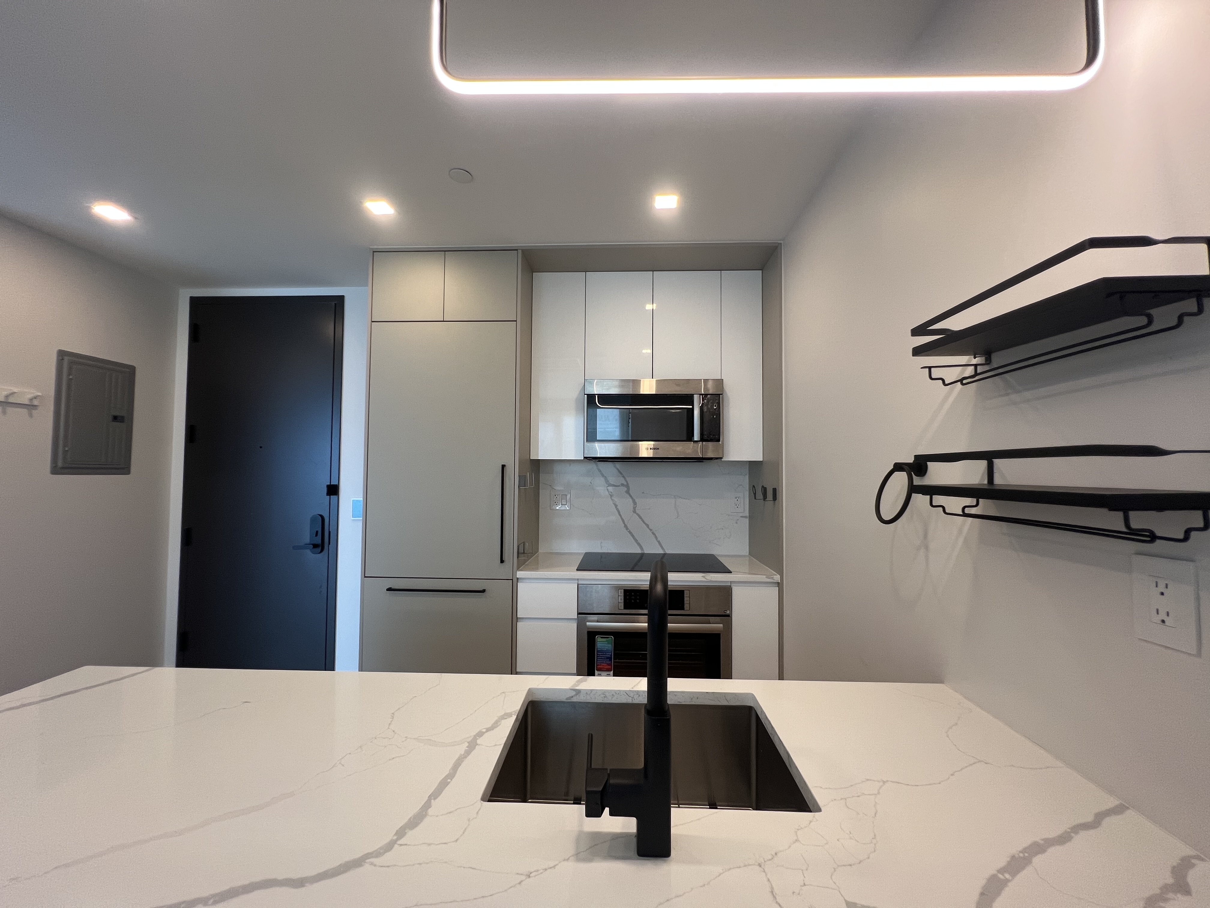 37-34 33rd Street, Unit 7H Queens, NY 11101 - Photo 3 of 18 a kitchen with kitchen island a counter top space a sink stainless steel appliances and cabinets