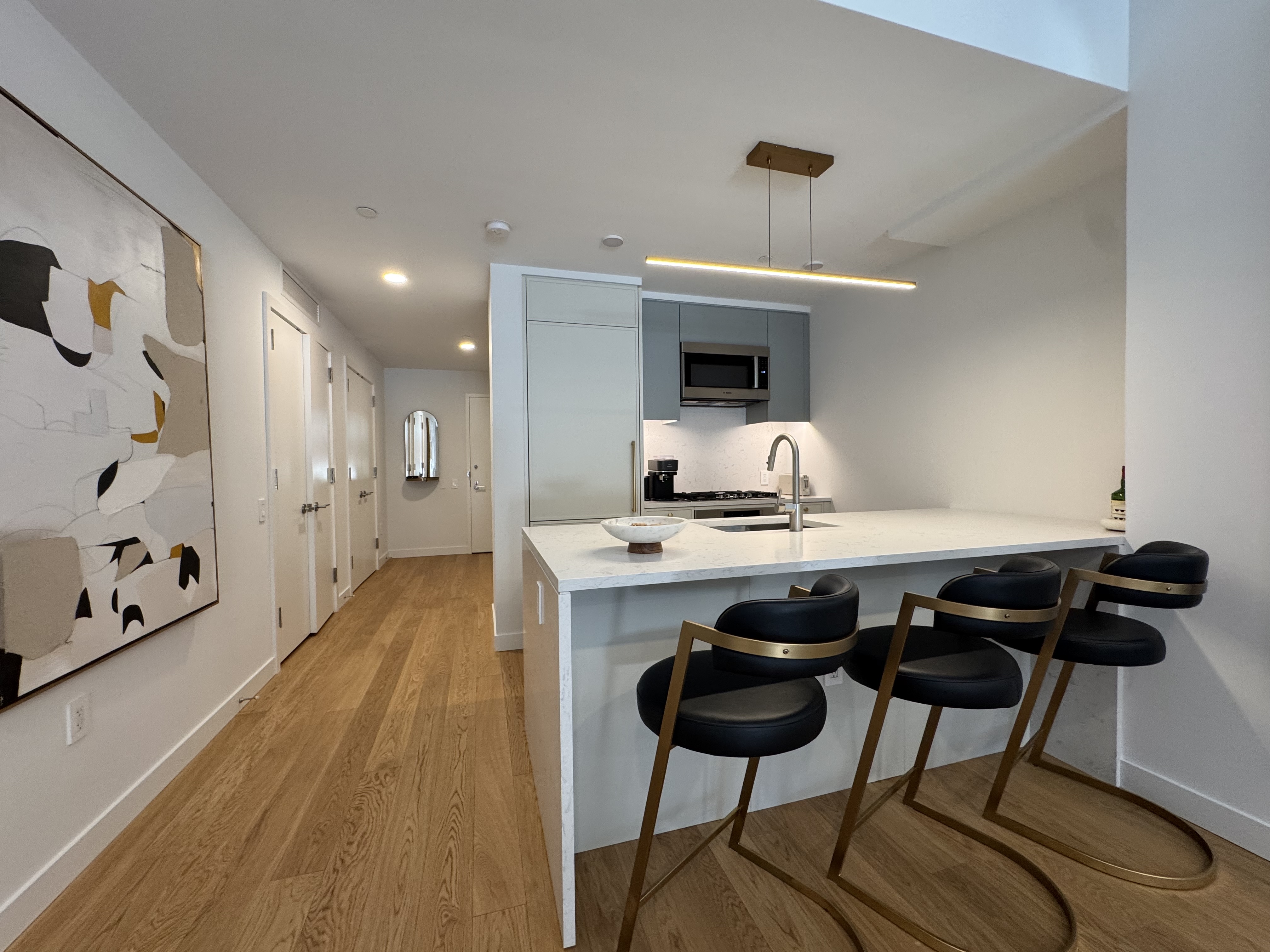 18 West 55th Street, Unit 7B Manhattan, NY 10019 - Photo 8 of 20 a kitchen with a table chairs refrigerator and sink