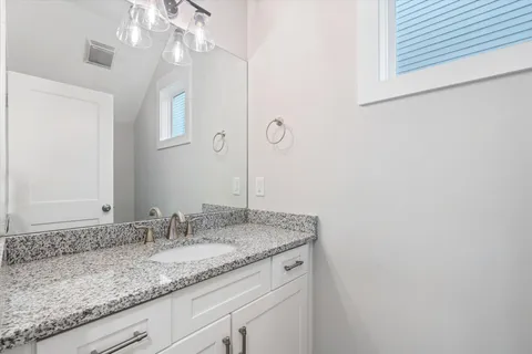 a bathroom with a granite countertop sink and a mirror