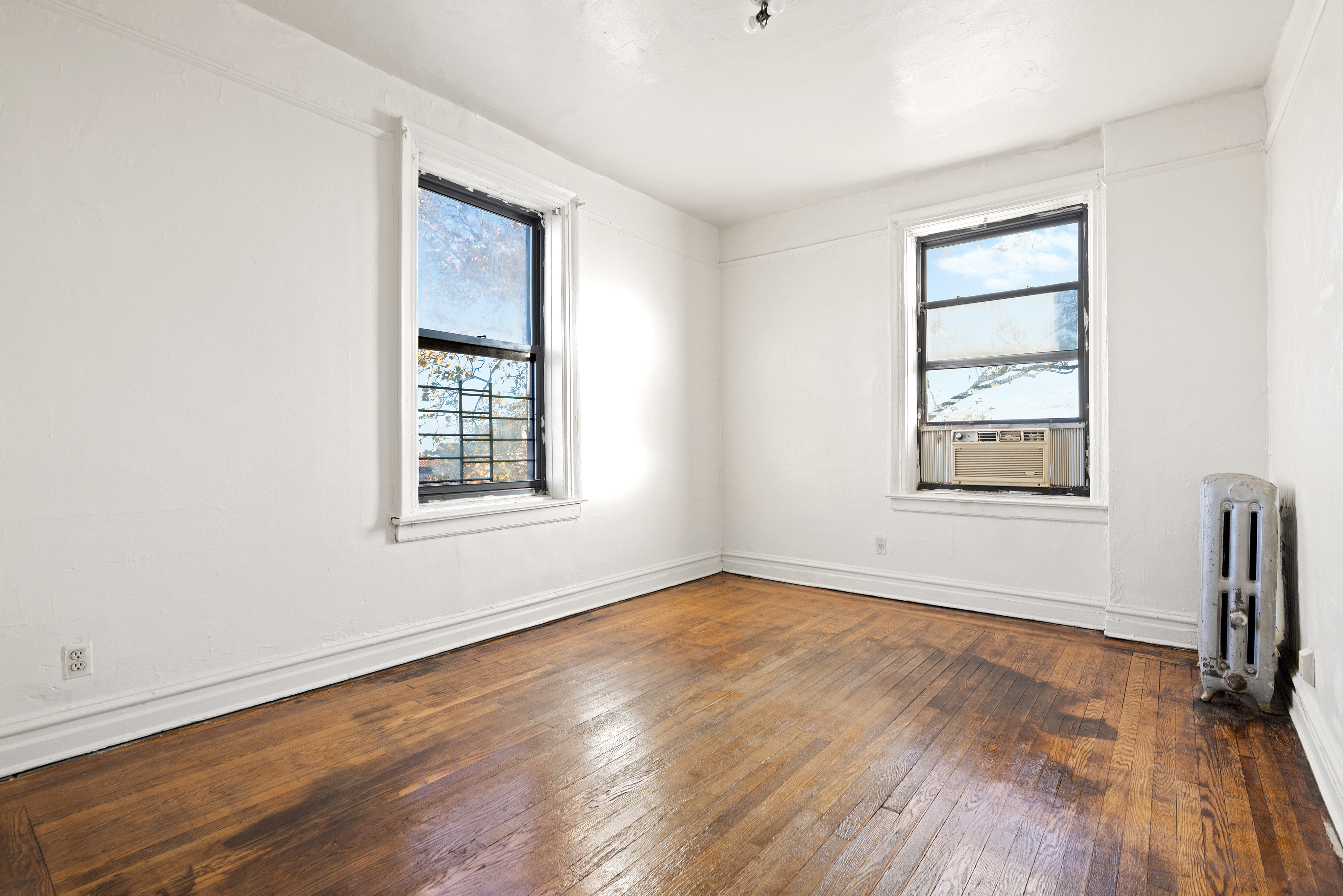 421 Crown Street, Unit 18R Brooklyn, NY 11225 - Photo 5 of 8 an empty room with wooden floor and windows