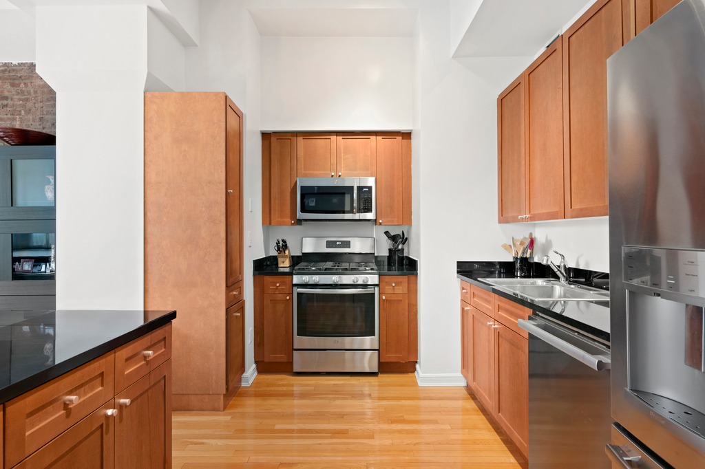 252 7th Avenue, Unit 10T Manhattan, NY 10001 - Photo 5 of 10 a kitchen with stainless steel appliances granite countertop a stove a sink and a microwave