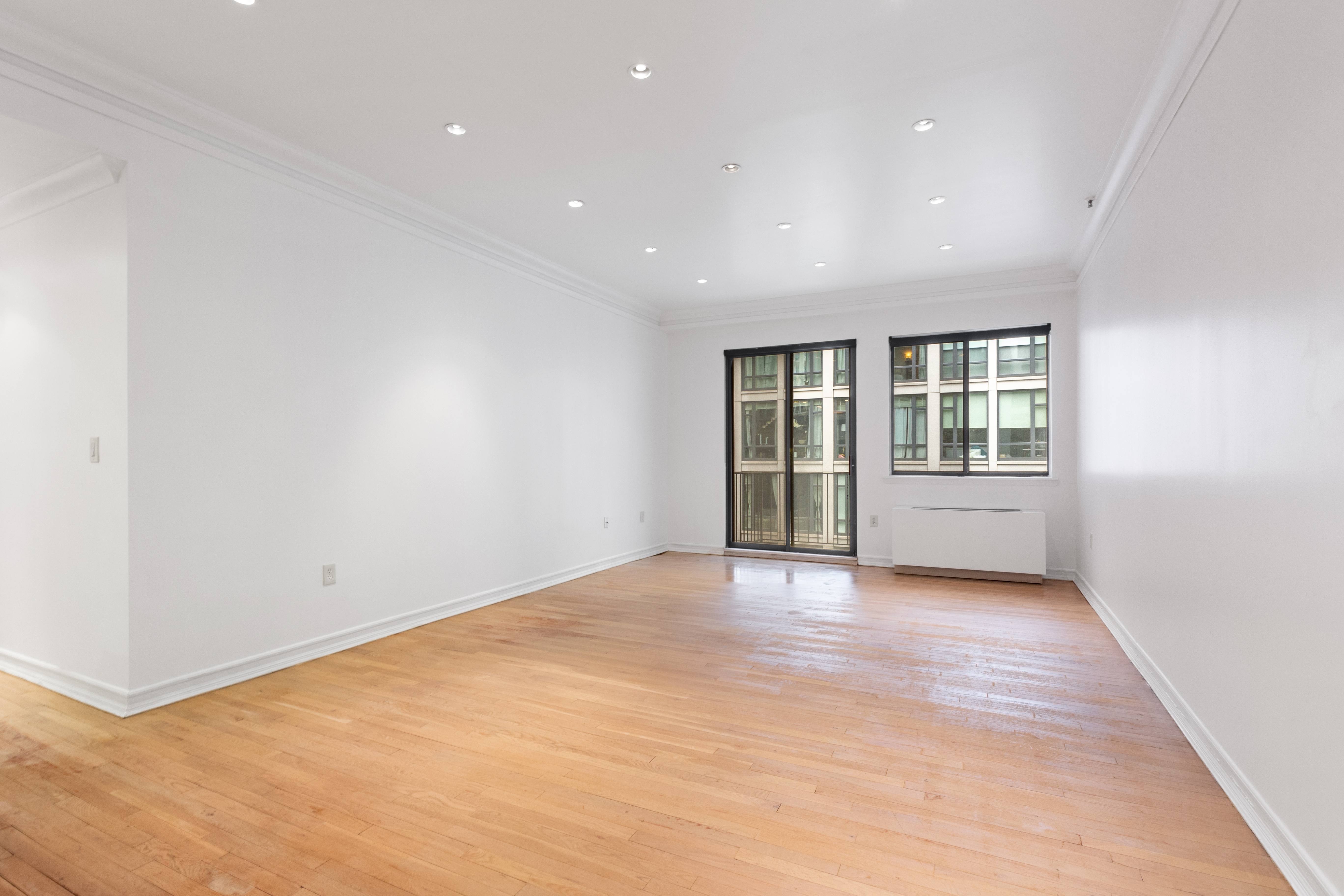 136-140 West 23rd Street, Unit 4CC Manhattan, NY 10011 - Photo 2 of 13 an empty room with wooden floor and windows