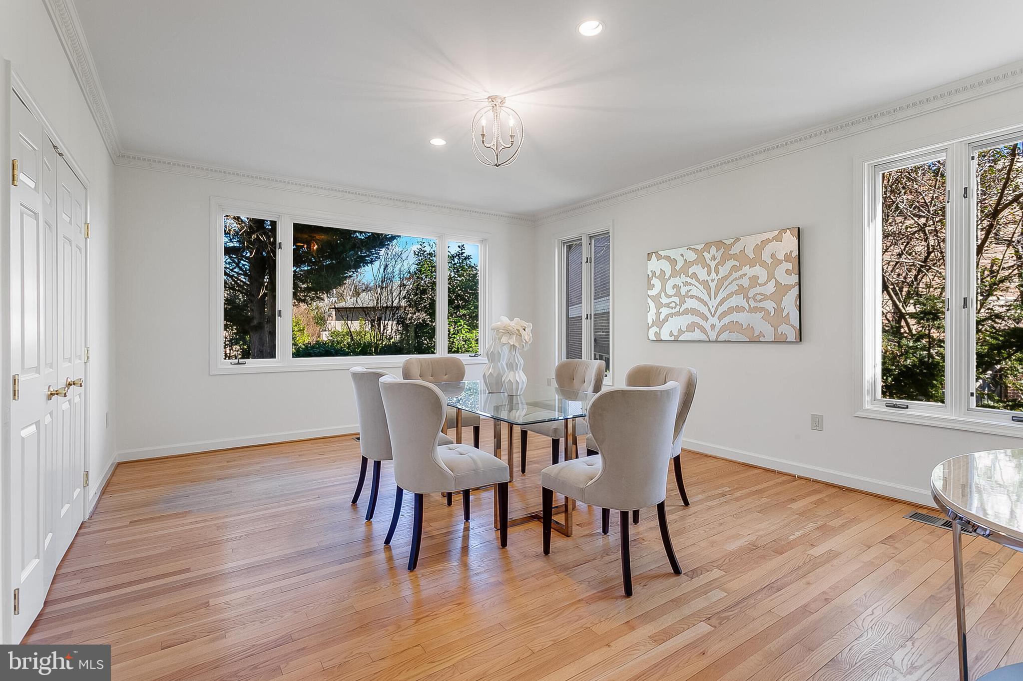 4709 Foxhall Crescent Northwest Washington, DC 20007 - Photo 18 of 57 a dining room with wooden floor a chandelier a glass table and chairs