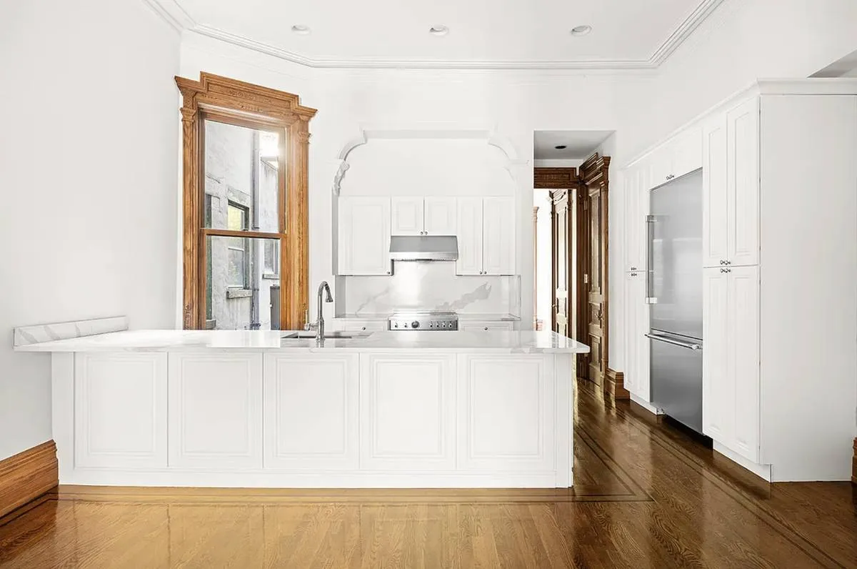 a large white kitchen with granite countertop a sink and a refrigerator