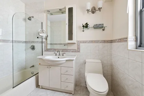 a bathroom with a toilet a sink a mirror and shower