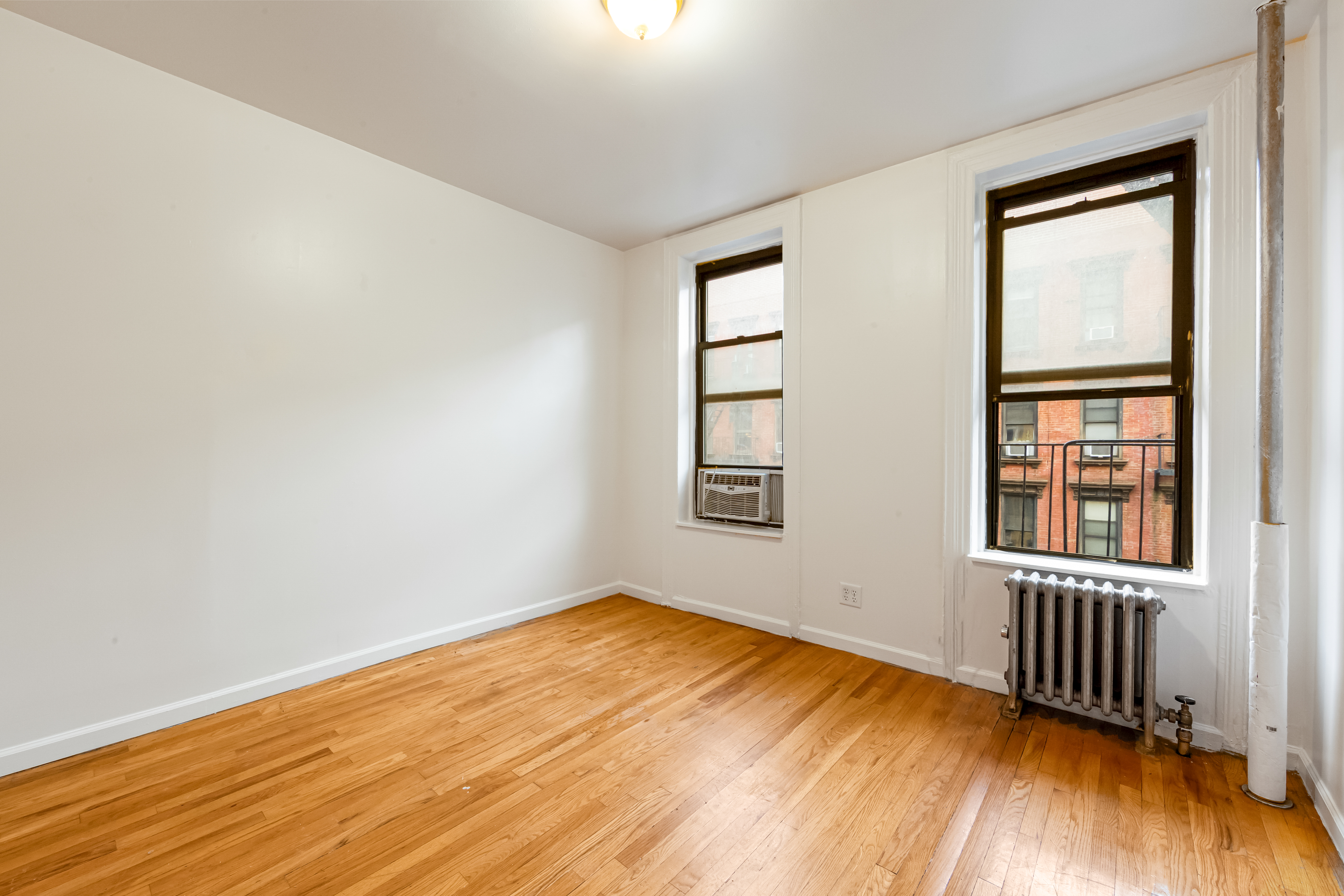 142 Sullivan Street, Unit 12 Manhattan, NY 10012 - Photo 3 of 12 an empty room with a window and wooden floor