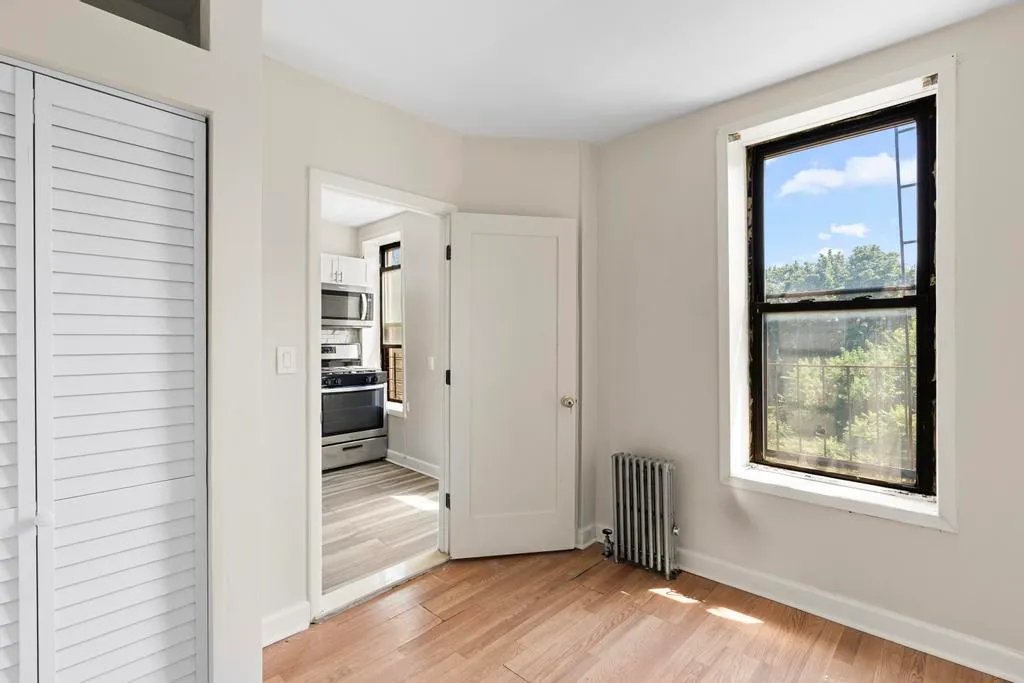 an empty room that has a window and wooden floor
