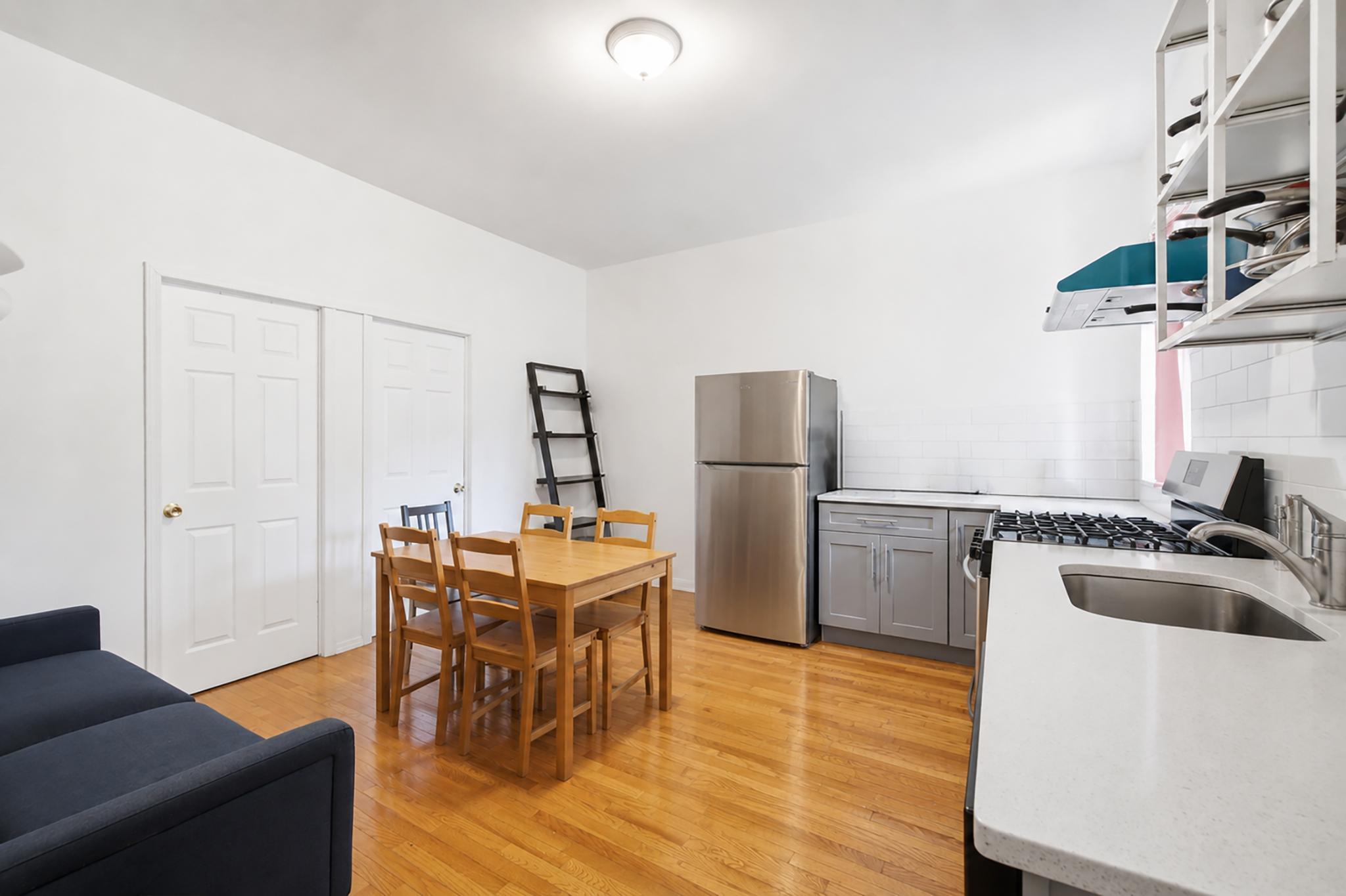 205 West 103rd Street, Unit 6B Manhattan, NY 10025 - Photo 3 of 11 a kitchen with a table chairs refrigerator and microwave