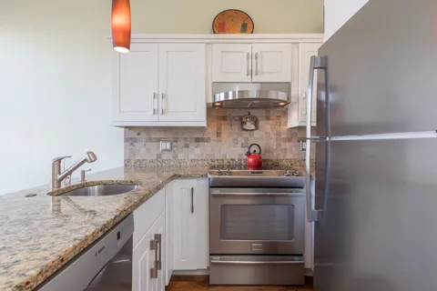 a kitchen with granite countertop white cabinets and white appliances