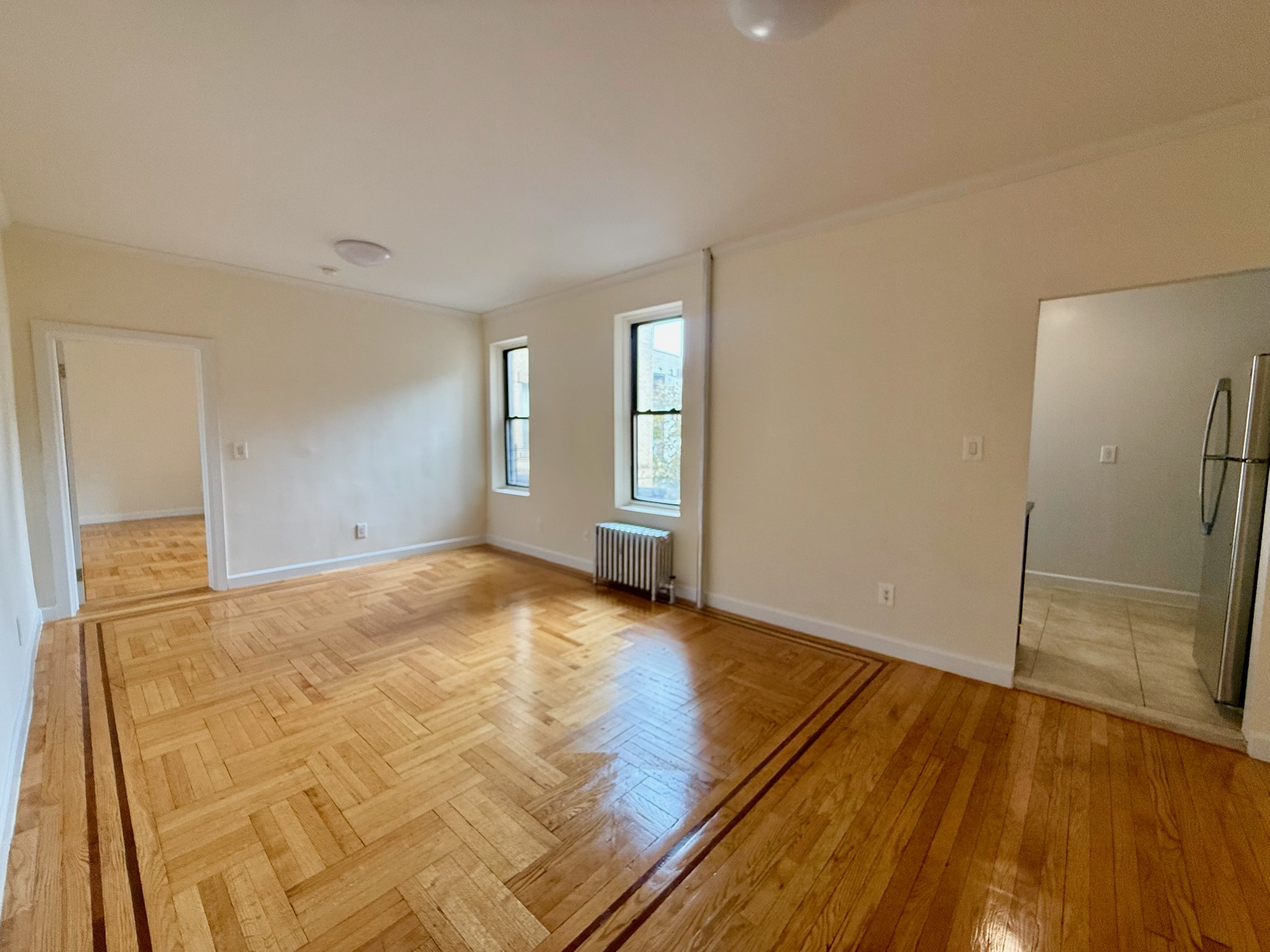 957 Greene Avenue, Unit BWEST Brooklyn, NY 11221 - Photo 2 of 8 an empty room with wooden floor and windows