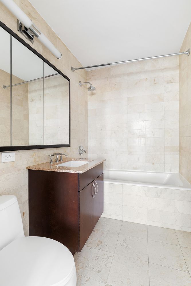 40 West 116th Street, Unit A808 Manhattan, NY 10026 - Photo 6 of 19 a bathroom with a bathtub shower sink vanity and mirror