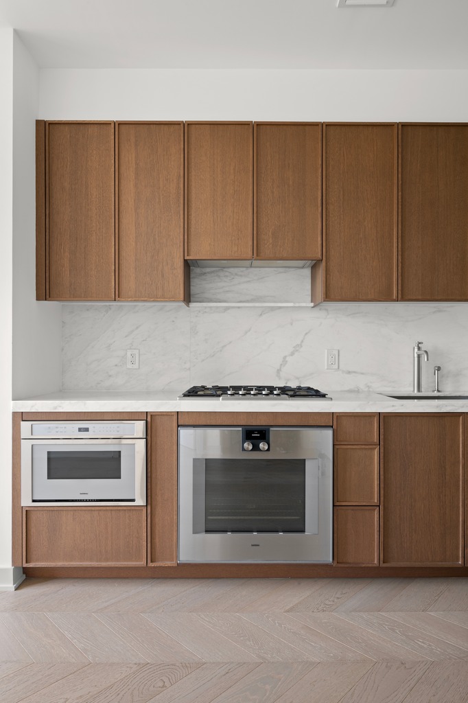 115 York Street, Unit 4J Brooklyn, NY 11201 - Photo 5 of 9 a kitchen with granite countertop white cabinets and stainless steel appliances