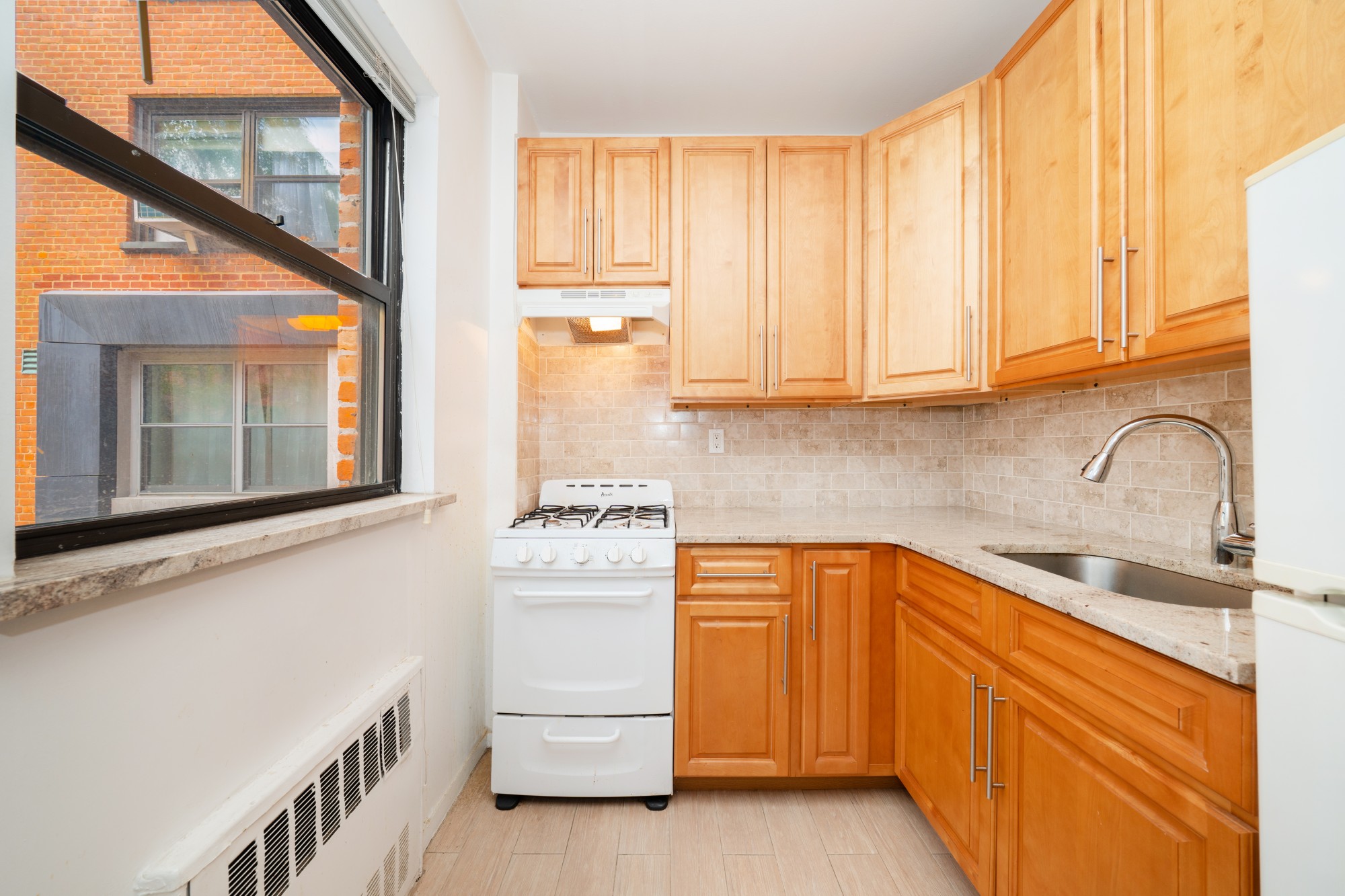 99-52 66th Road, Unit 1H Queens, NY 11374 - Photo 4 of 11 a kitchen with white cabinets and a sink