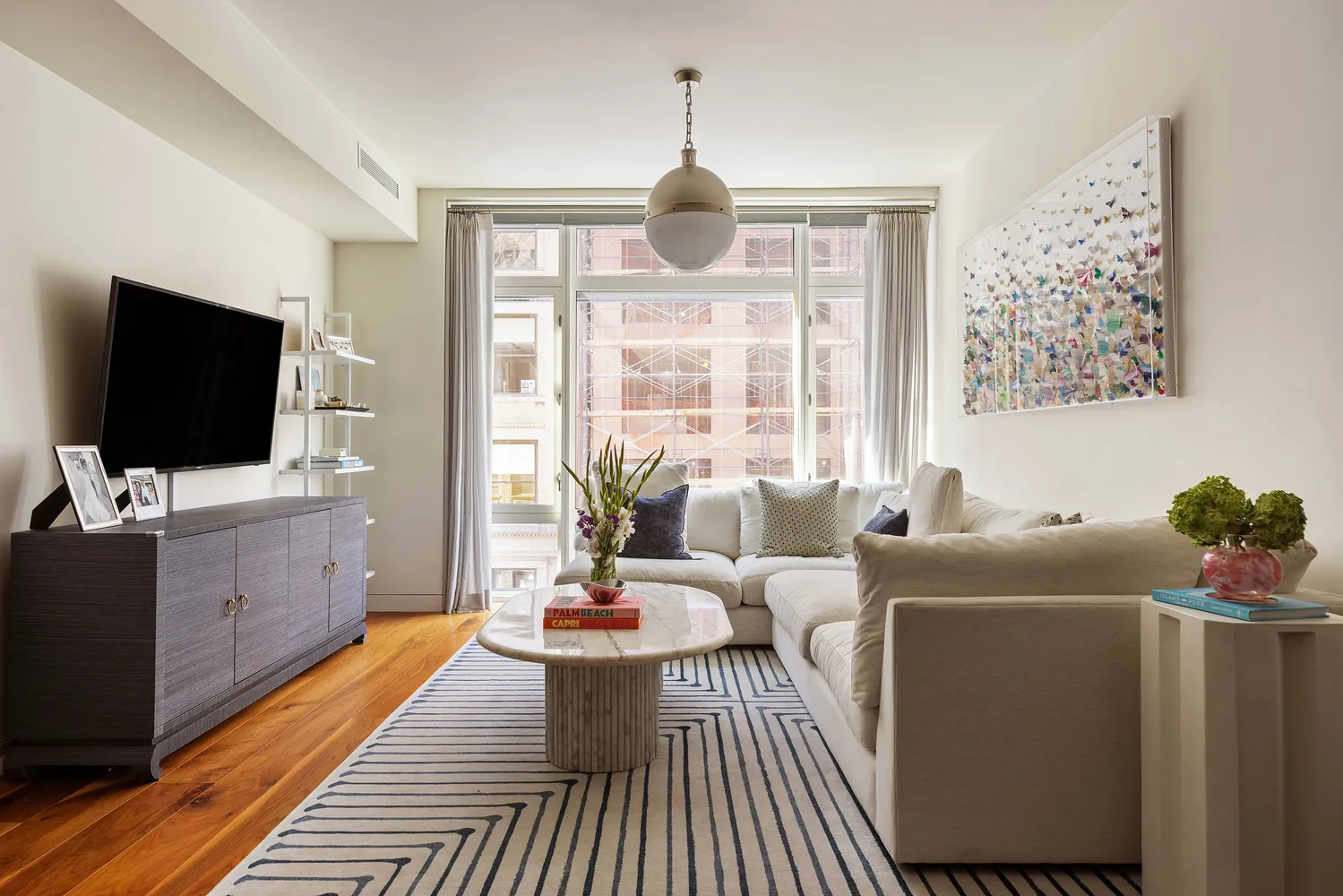 a living room with furniture a flat screen tv and a floor to ceiling window