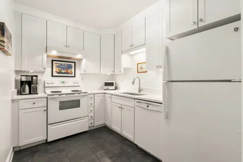 a kitchen with white cabinets and white appliances