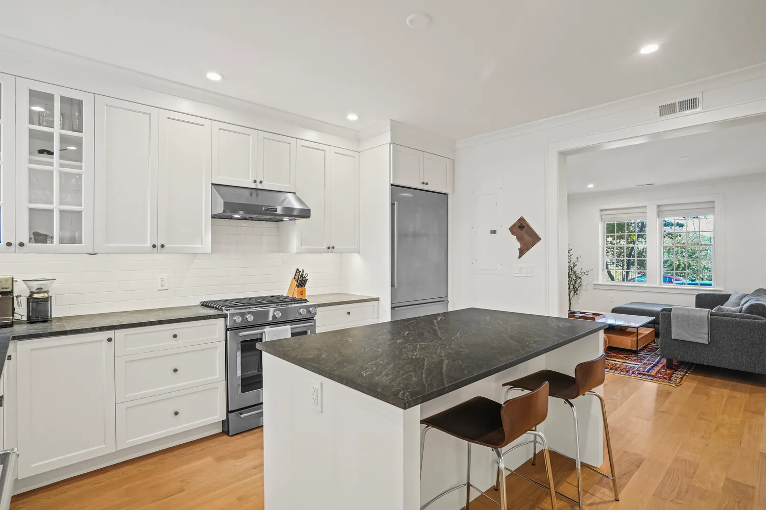 a kitchen with granite countertop a stove a sink a dining table and chairs