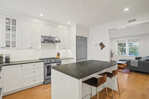 a kitchen with granite countertop a stove a sink a dining table and chairs