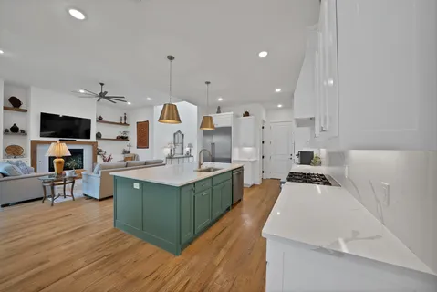 a large kitchen with stainless steel appliances kitchen island granite countertop a large stove a sink dishwasher and white cabinets with wooden floor