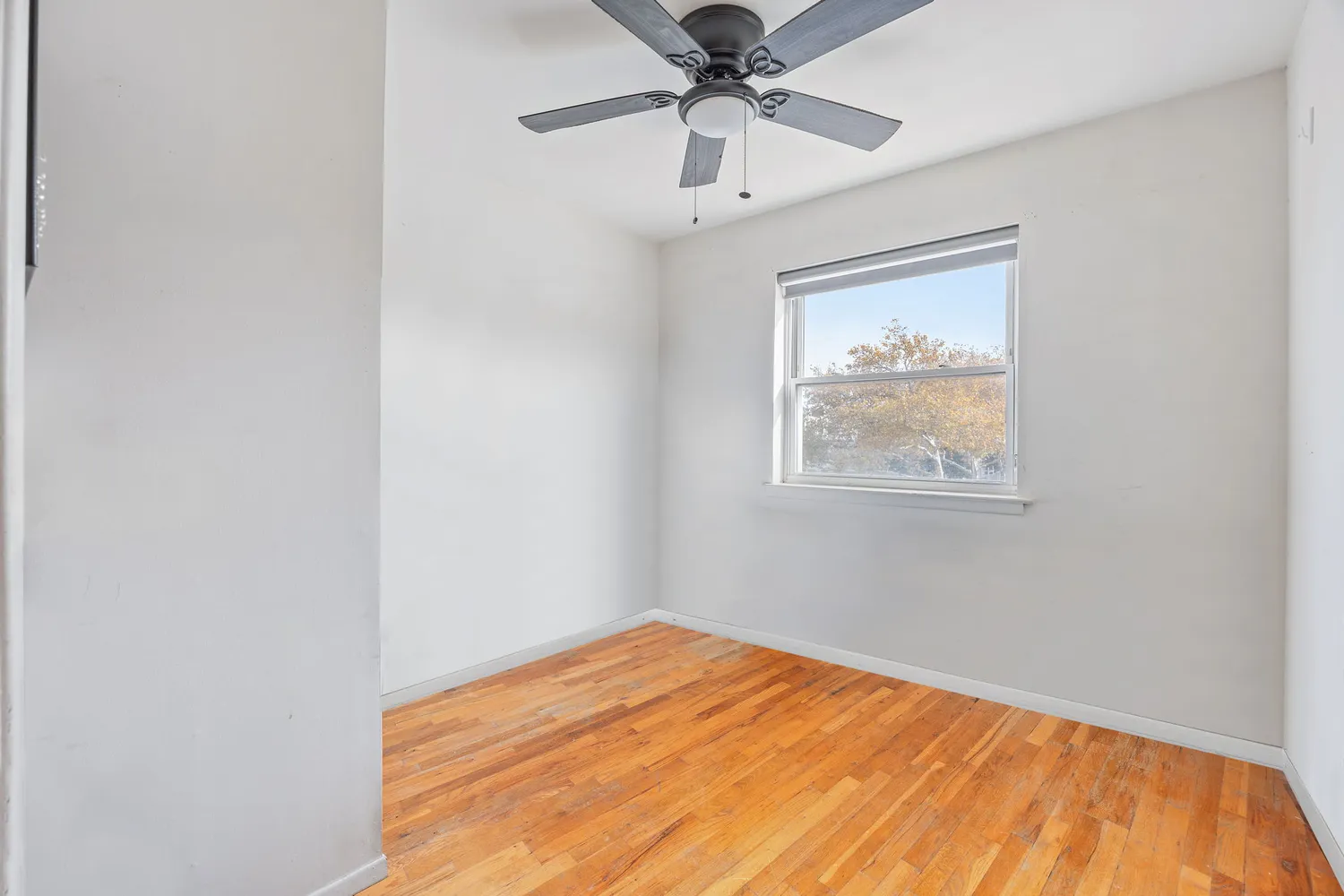 an empty room with a window and a ceiling fan