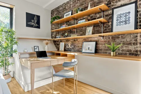 a living room with stainless steel appliances wooden floor and a window