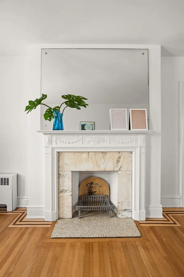 a view of an empty room with wooden floor and a fireplace