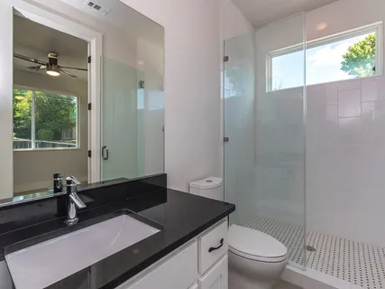 a bathroom with a granite countertop sink toilet and shower