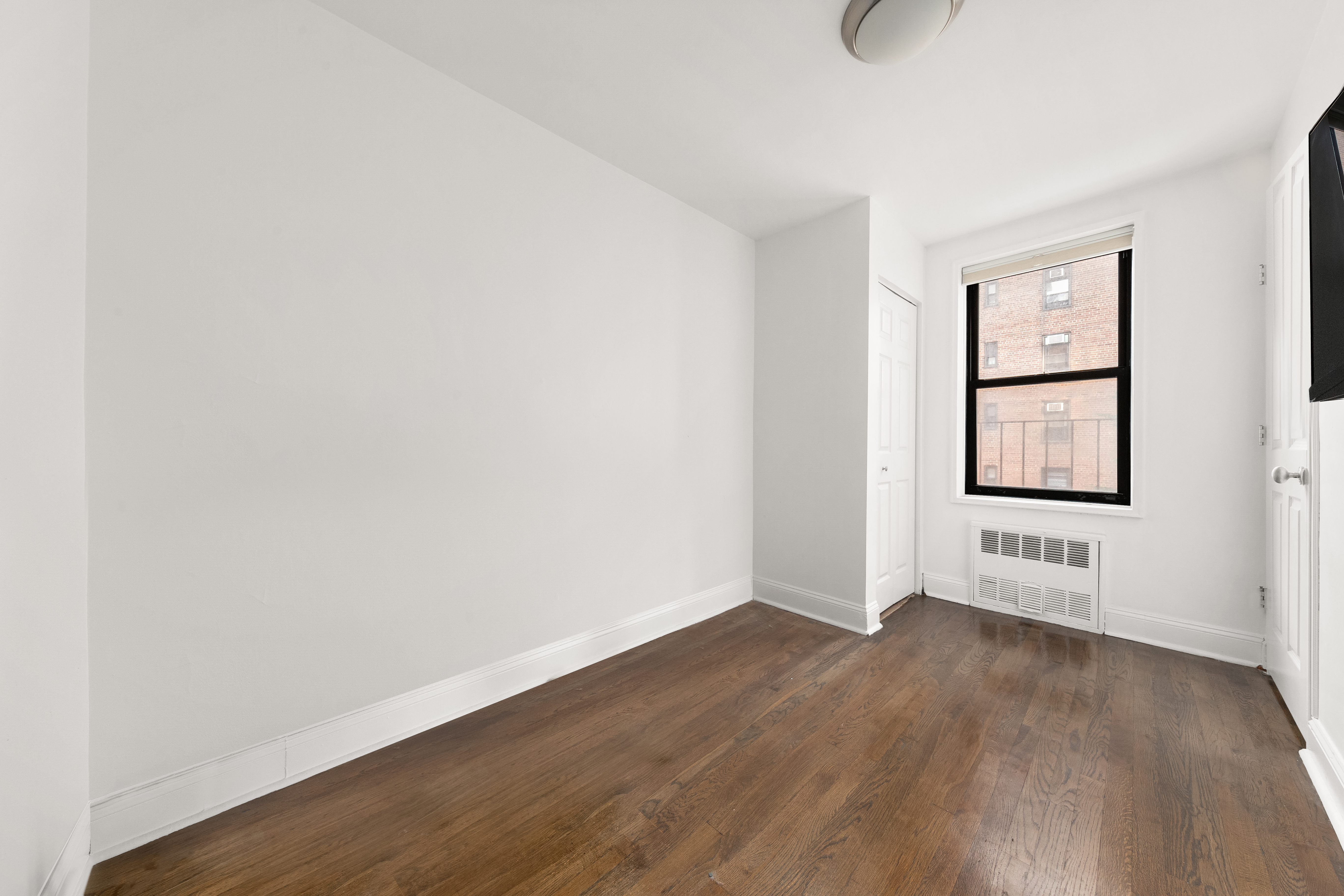 140 7th Avenue, Unit 4M Manhattan, NY 10011 - Photo 4 of 7 an empty room with wooden floor and windows