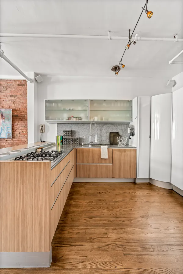 a large white kitchen with wooden floor and a sink