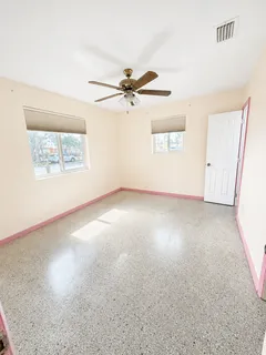 an empty room with windows and fan