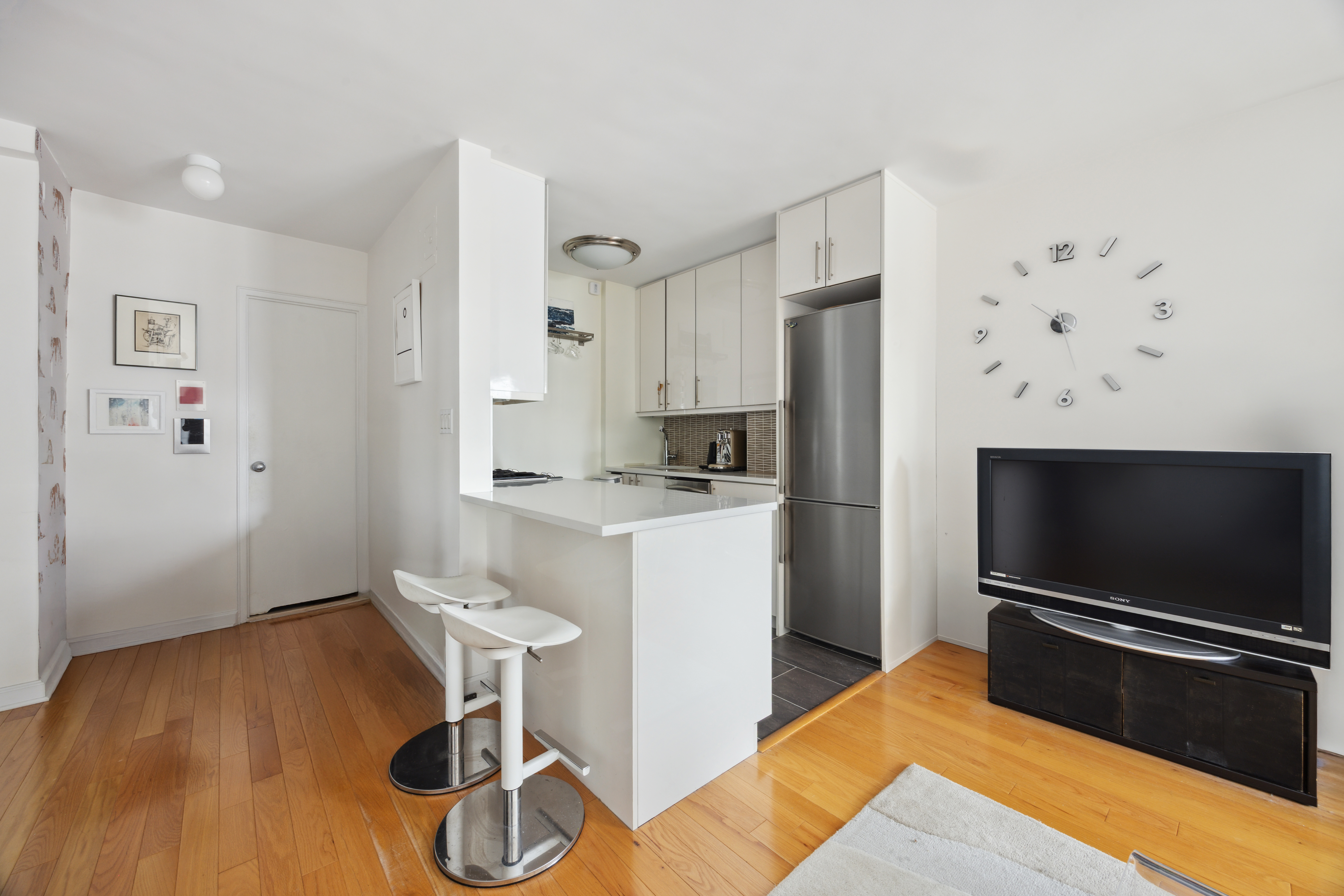 240 East 76th Street, Unit 14A Manhattan, NY 10021 - Photo 3 of 8 a kitchen with stainless steel appliances wooden floor and chair
