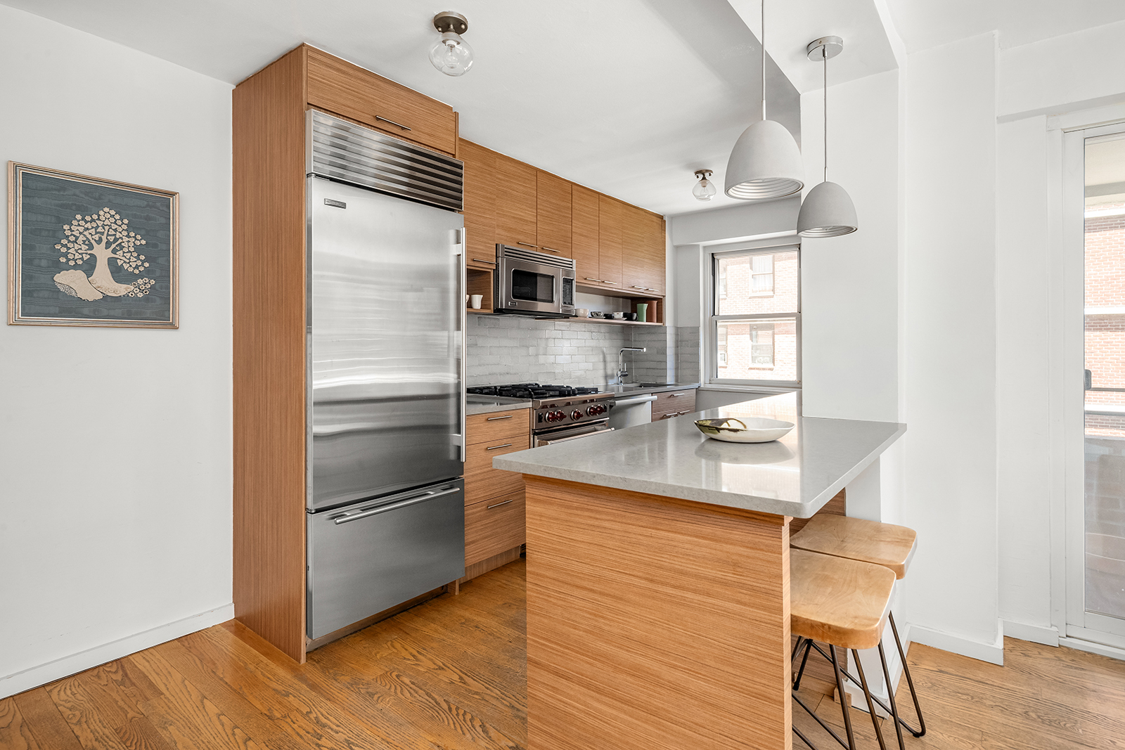 383 Grand Street, Unit M1304 Manhattan, NY 10002 - Photo 3 of 9 a kitchen with kitchen island a counter top space cabinets and stainless steel appliances