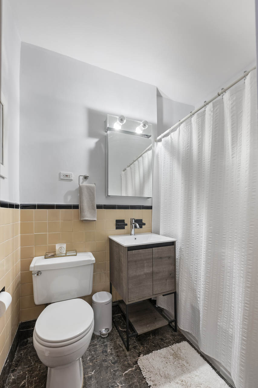 242 East 87th Street, Unit 2B Manhattan, NY 10128 - Photo 6 of 10 a bathroom with a toilet a sink and a shower