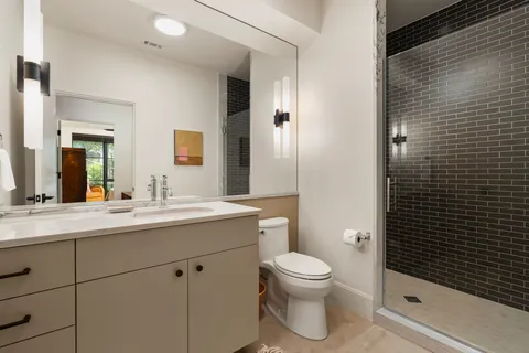 a bathroom with a sink a toilet a mirror and shower