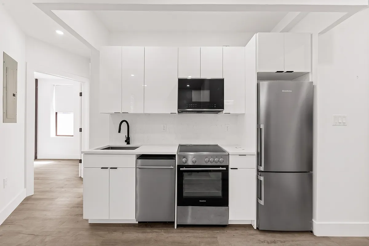 301 East 90th Street, Unit 4C Manhattan, NY 10128 - Photo 6 of 11 a kitchen with stainless steel appliances white cabinets and a refrigerator