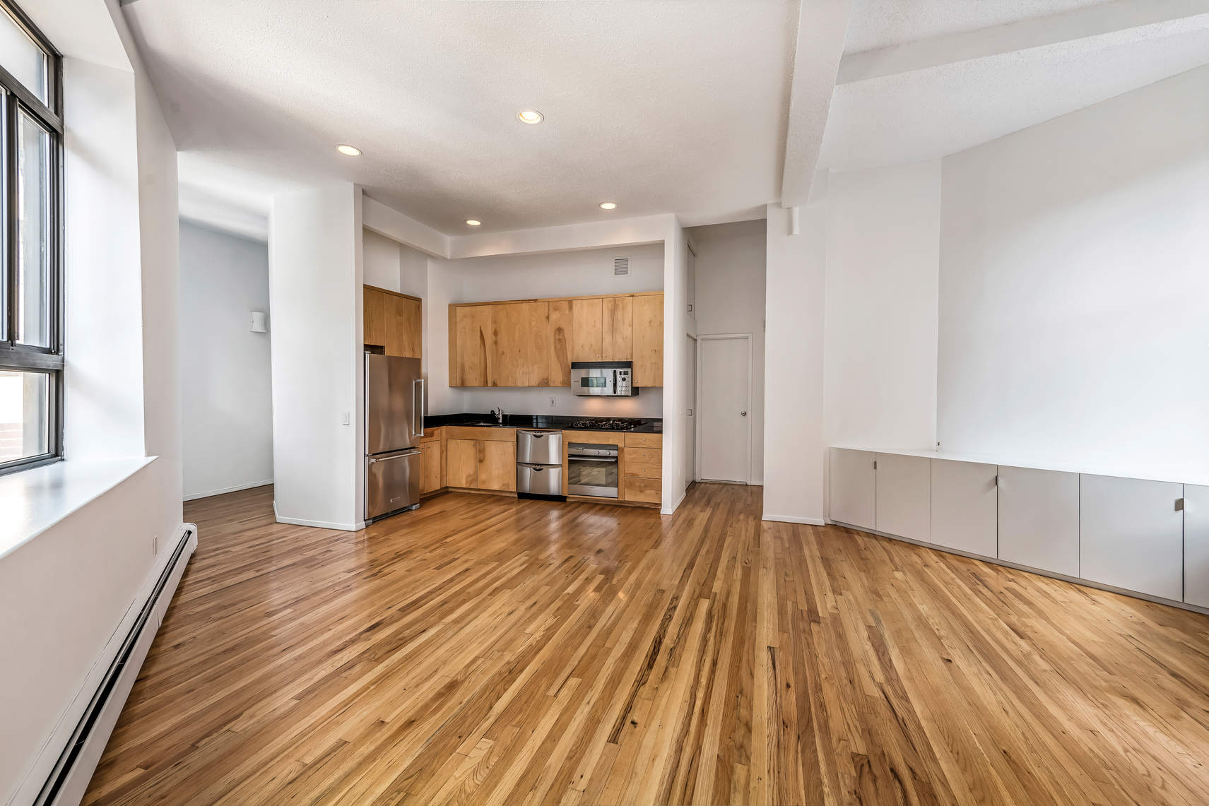 2 Cornelia Street, Unit 306 Manhattan, NY 10014 - Photo 5 of 13 a view of a kitchen with wooden floor and electronic appliances
