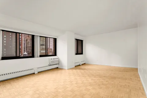a view of an empty room with chandelier fan and window