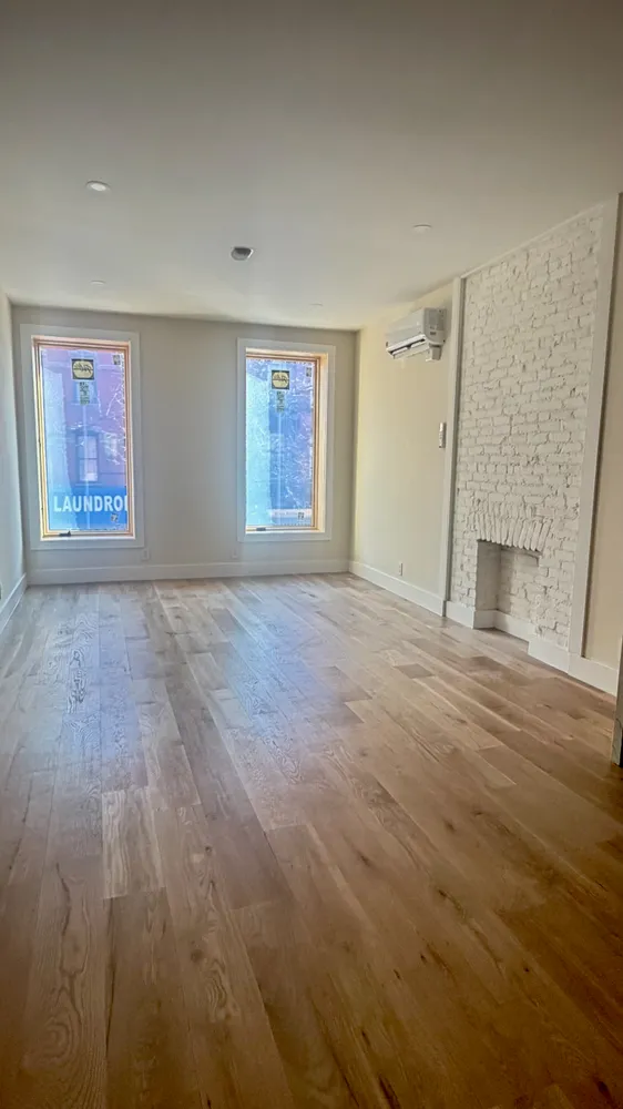 an empty room with windows and fireplace