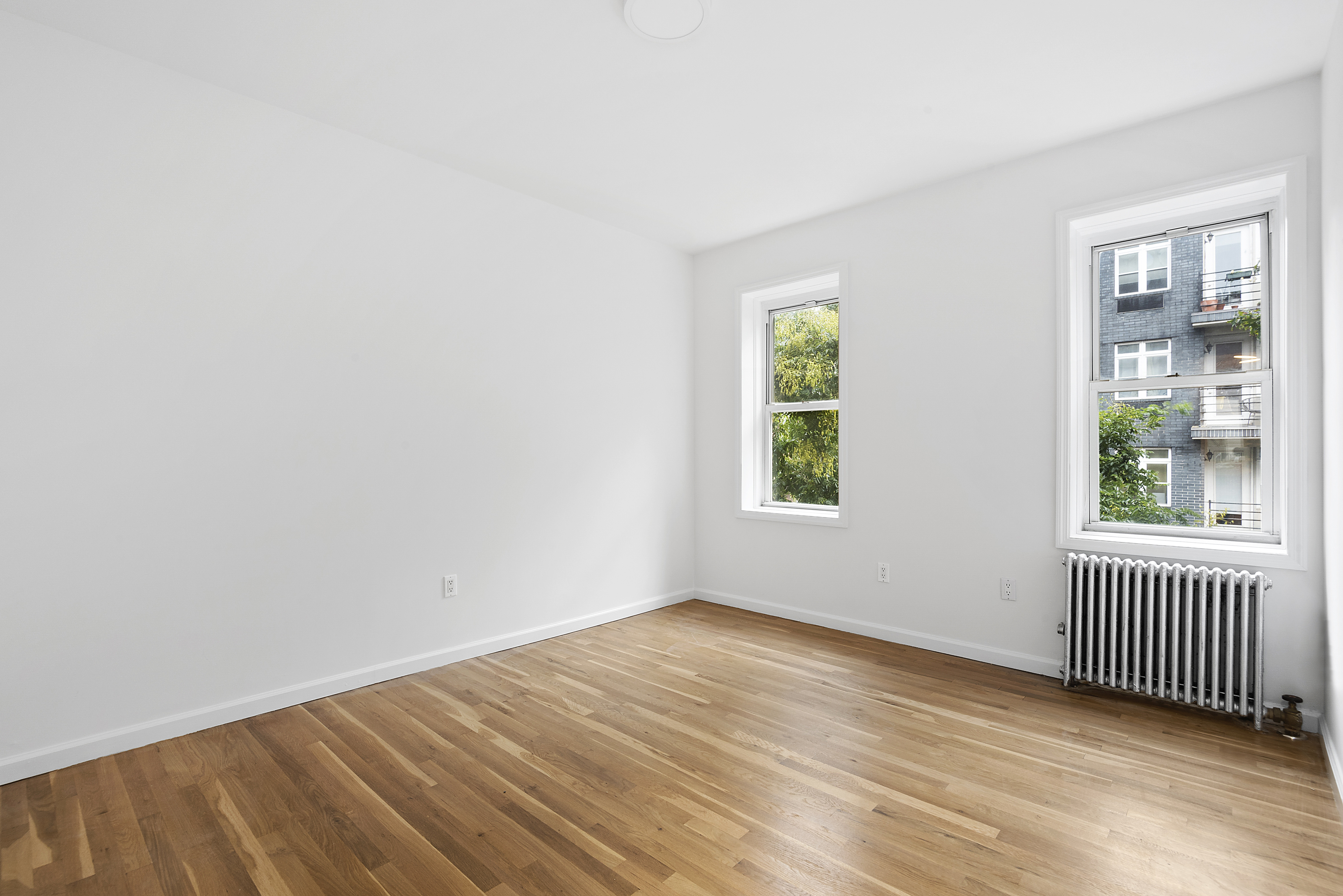 59 Stagg Street, Unit 3 Brooklyn, NY 11206 - Photo 3 of 8 an empty room with wooden floor and windows