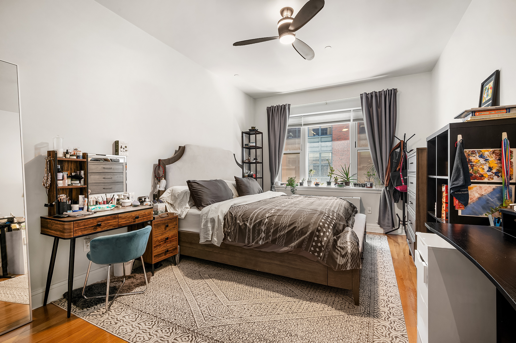 41-26 27th Street, Unit 5E Queens, NY 11101 - Photo 8 of 12 a bedroom with a bed a bookshelf and a bookshelf
