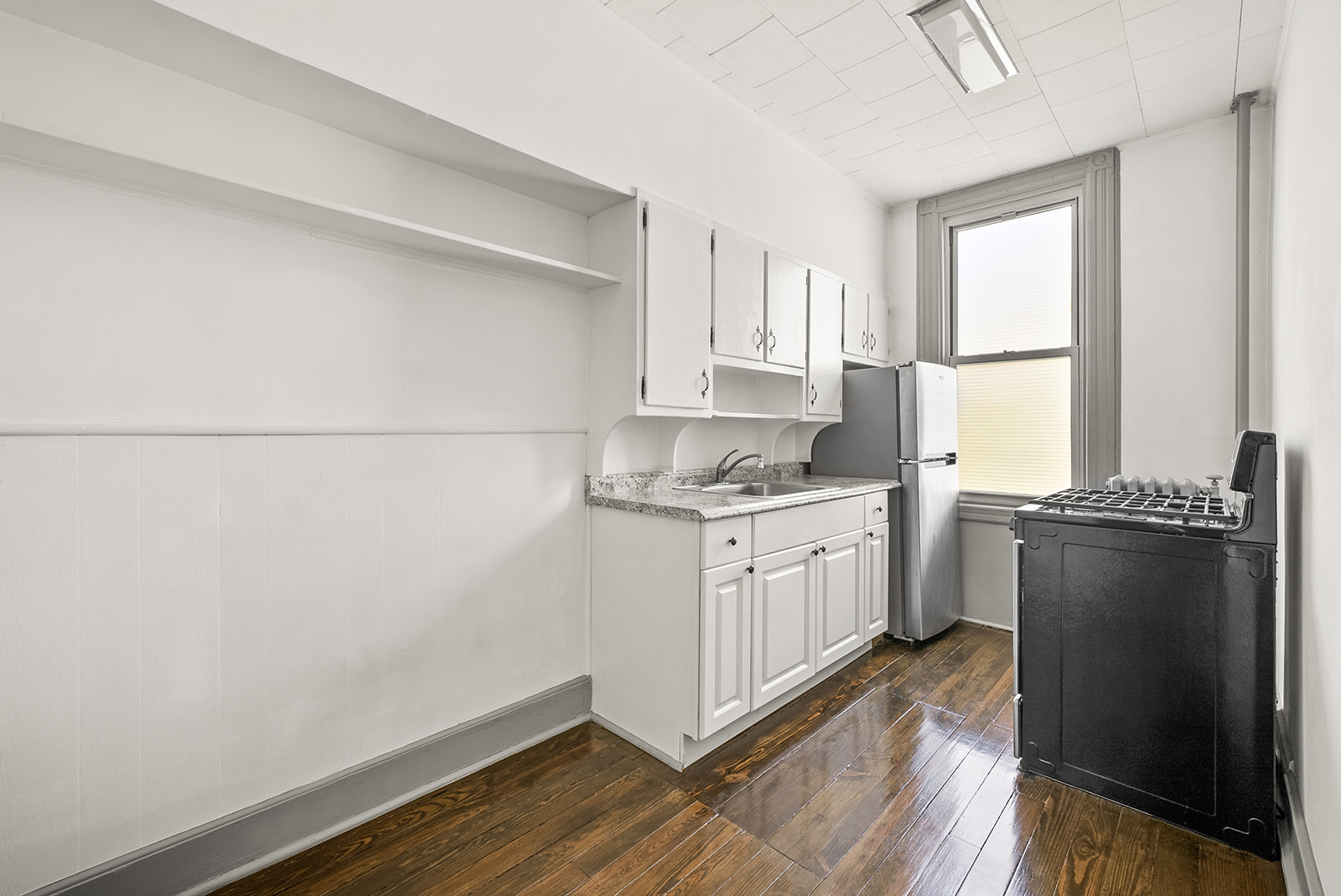 59-45 Palmetto Street Queens, NY 11385 - Photo 5 of 25 a kitchen with granite countertop a refrigerator a sink and white cabinets