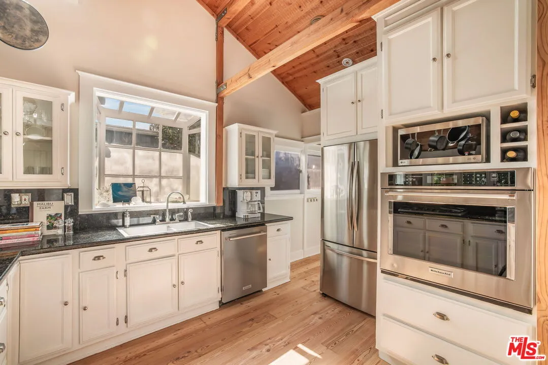 a kitchen with granite countertop stainless steel appliances cabinets a sink and a window