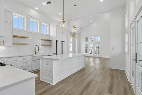 a kitchen with stainless steel appliances granite countertop white cabinets and a chandelier