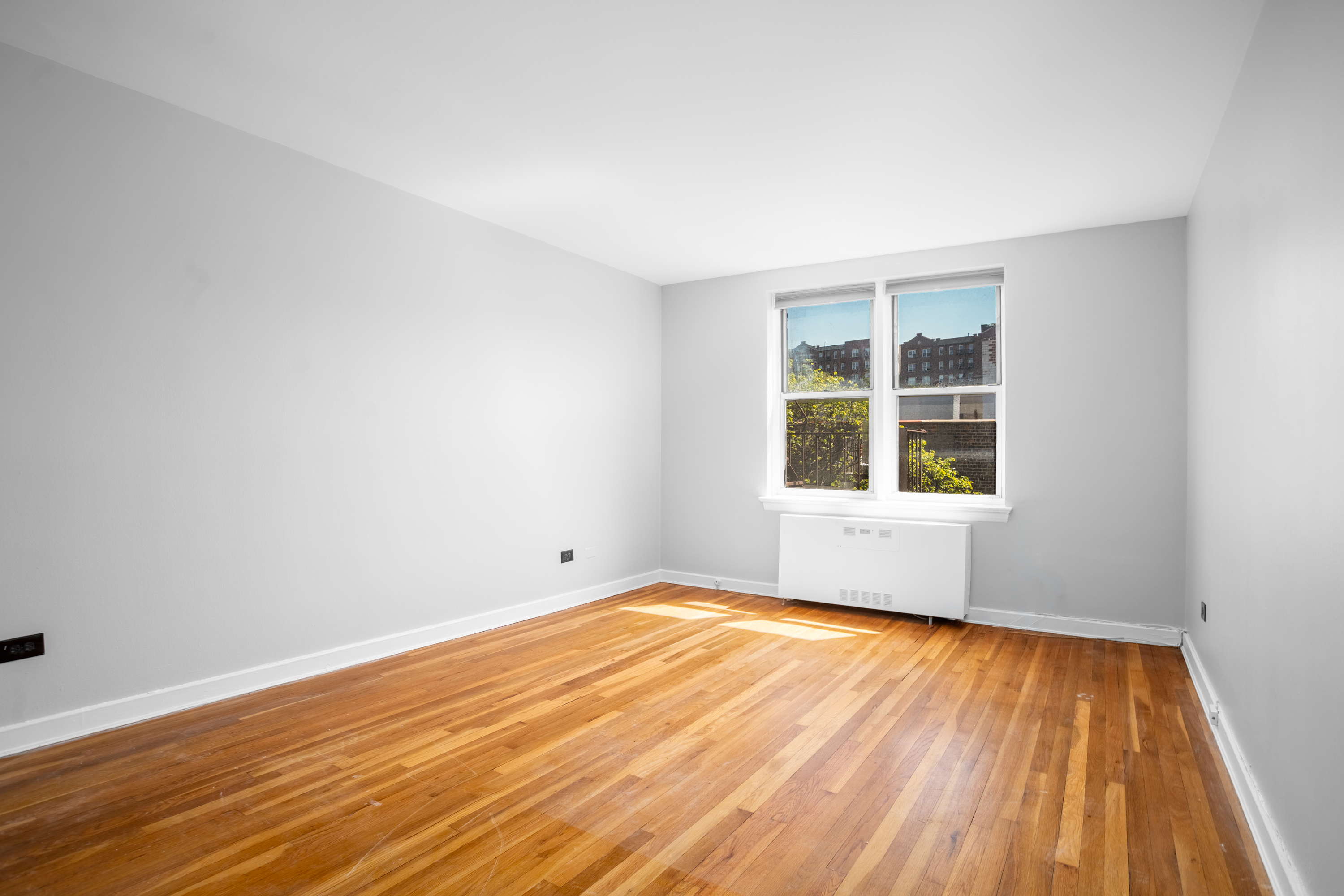 143 Bennett Avenue, Unit 6R Manhattan, NY 10040 - Photo 4 of 22 a view of an empty room with wooden floor and a window